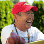 Pear grower Gordy Sato in a red hat laughing