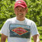 Pear grower Gordy Sato in a Hood River T-shirt and a red hat in his orchards in Parkdale, Oregon