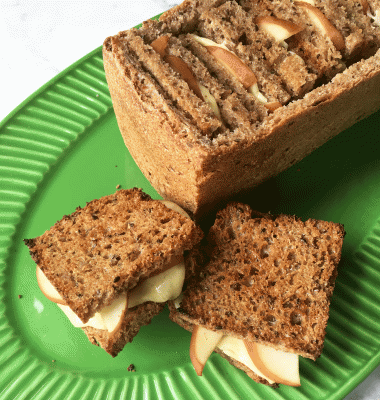 Small, grilled cheese and pear squares stuffed into a bread crust "basket" on a green plate